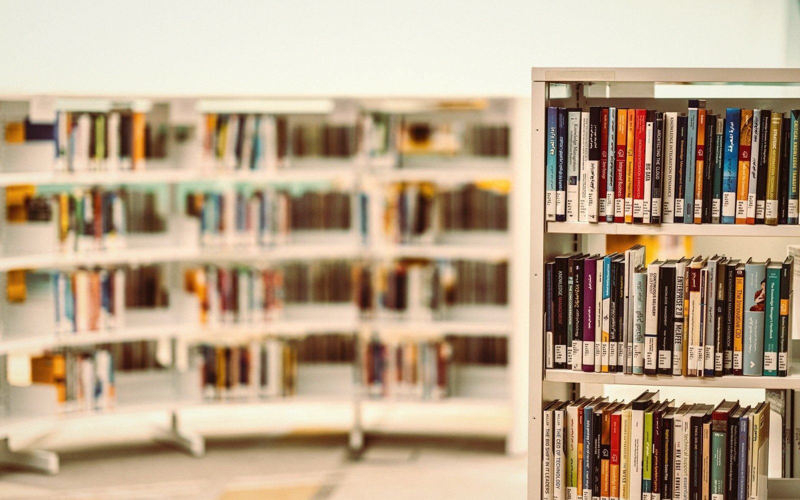 Rows of curved library shelves with colorful book spines, one shelf in sharp focus